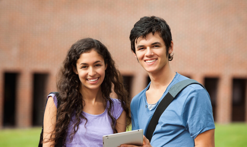 A teenage boy and a teenage girl smiling